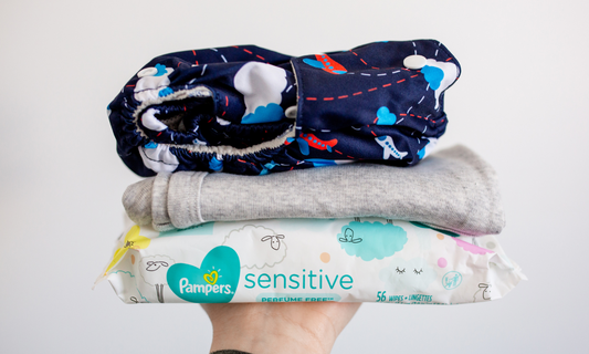 Simple Being cloth diaper folded on top of a grey onesie